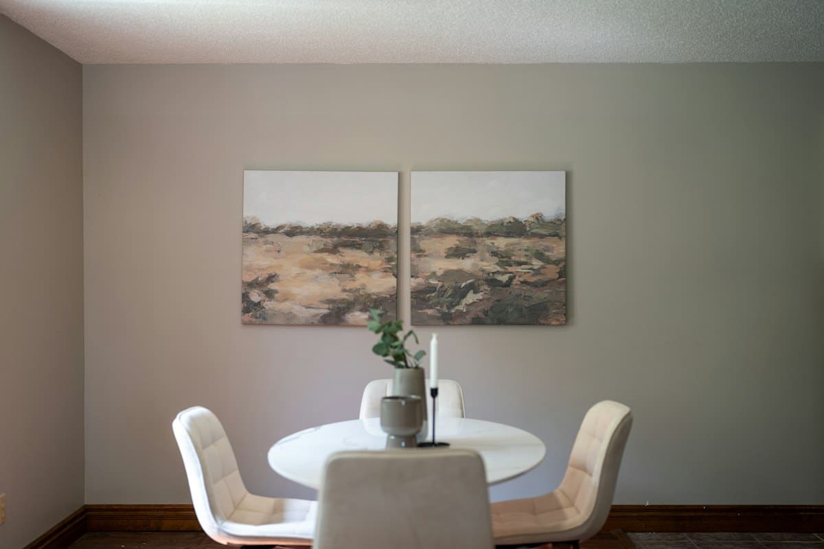 Pintura abstrata de paisagem em tons terrosos, em dois painéis, sobre uma mesa de jantar