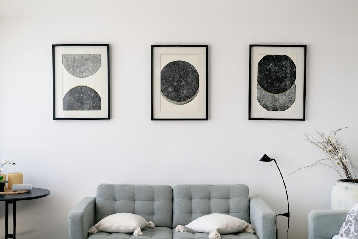 Três estampas circulares abstratas a preto e branco sobre um sofá cinzento